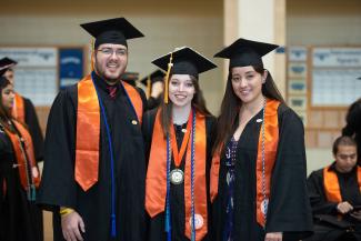 Three students smiling at graduation